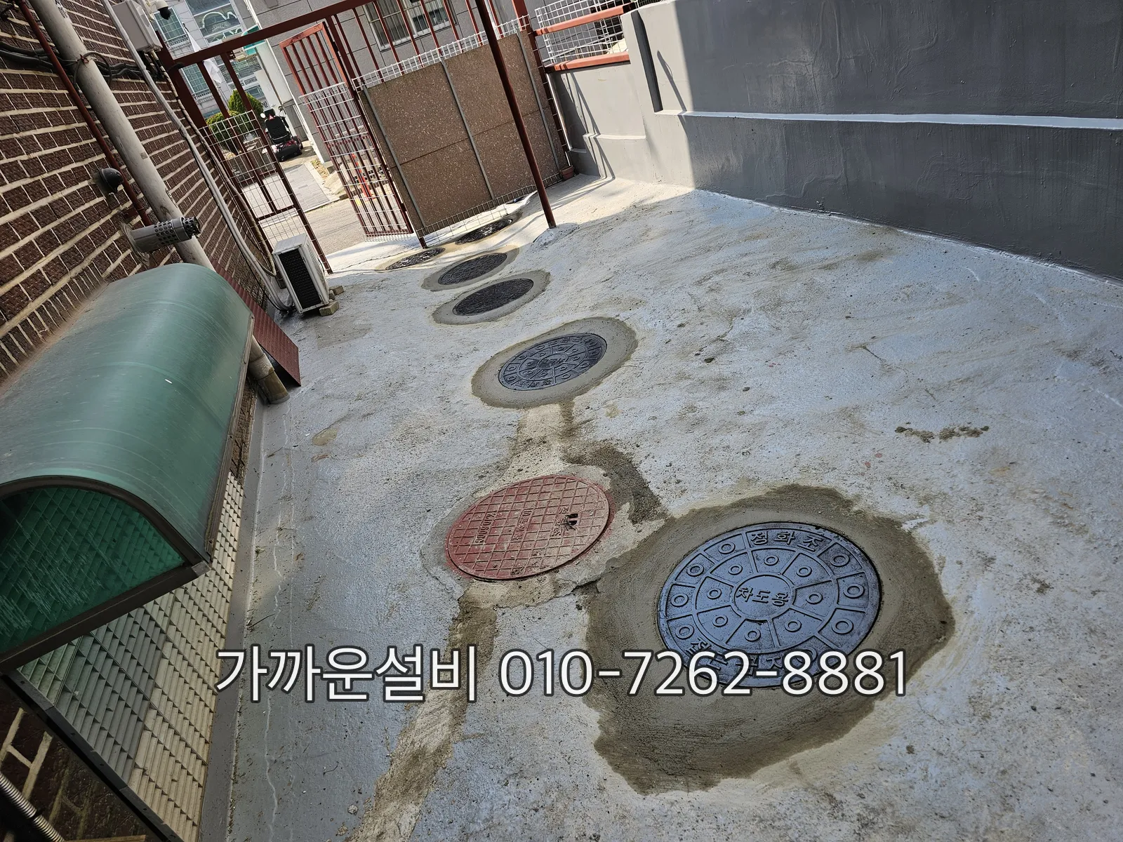 건물 마당 바닥에 오수 맨홀과 우수 맨홀 뚜껑이 나란히 있는 모습