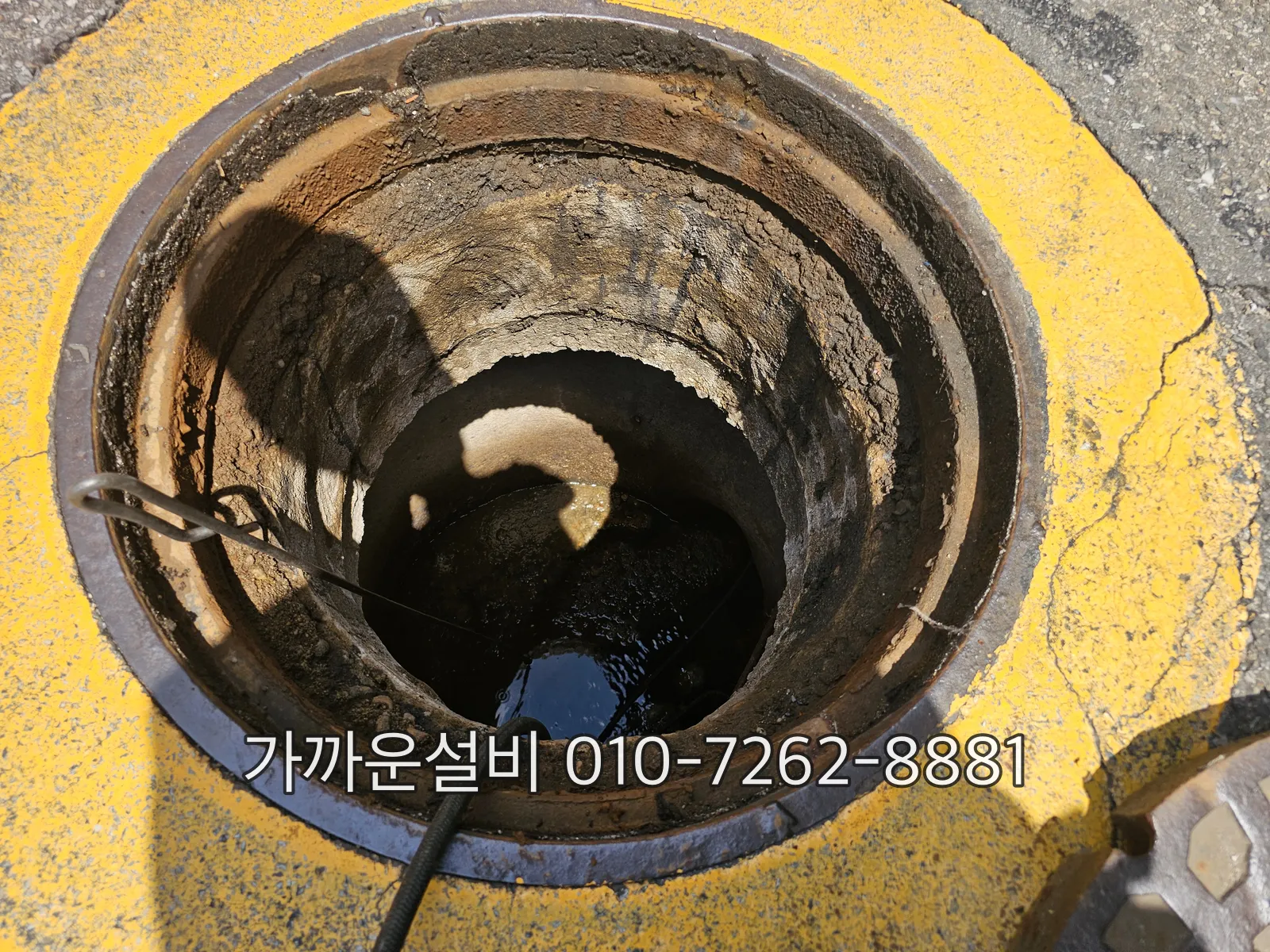 옥외 우수 맨홀을 열고 세척 호스를 넣어 안에 고인 물과 침전물을 확인하는 모습