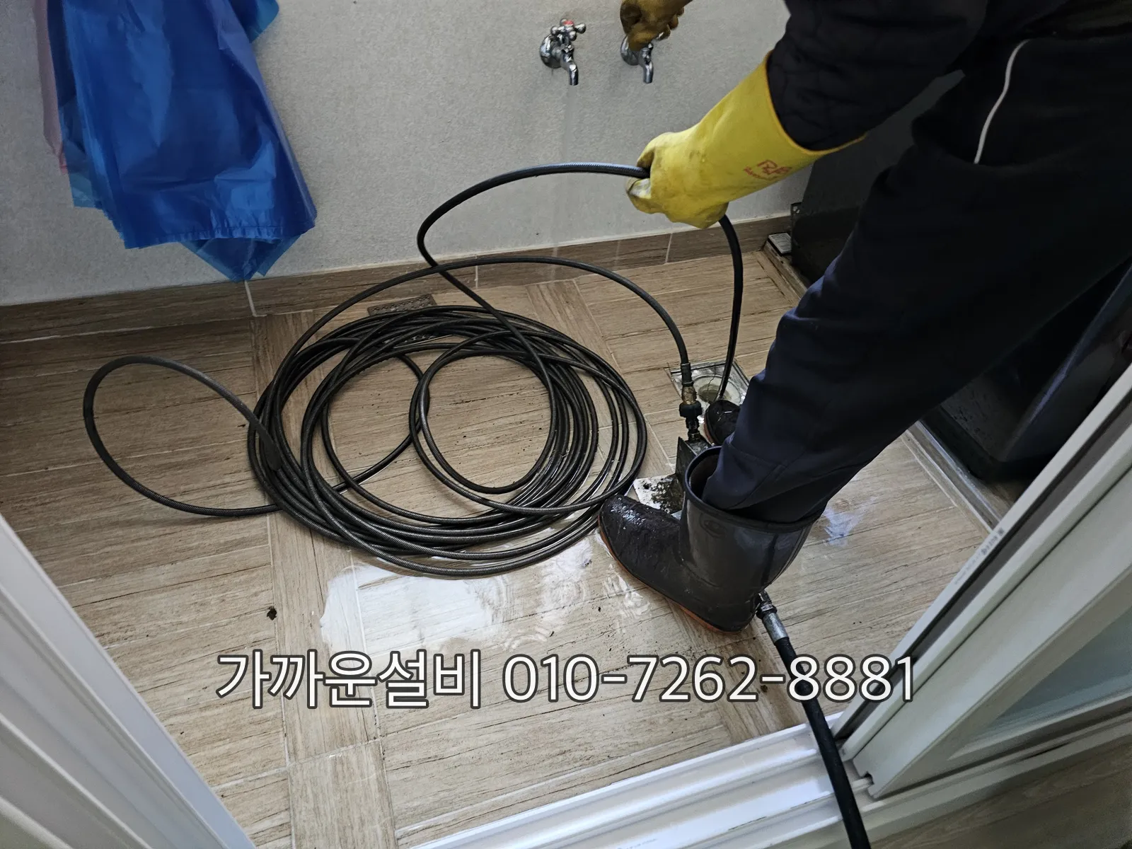 베란다 우수관 배수구에 장갑 낀 손으로 케이블을 넣어 작업하는 모습